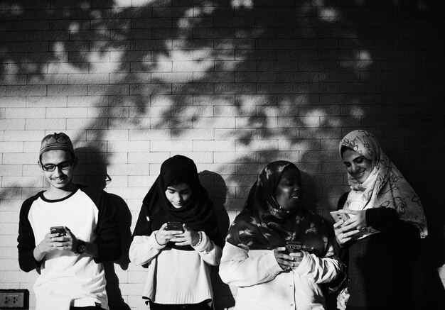 Um grupo de estudantes muçulmanos usando telefones celulares