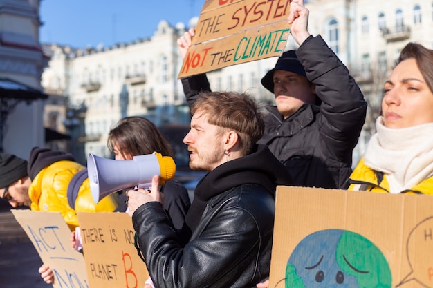 Foto grátis um grupo de pessoas com faixas e um megafone na mão protestam na praça da cidade por svae planet clean world act now