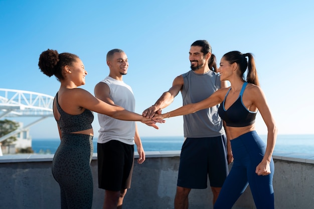 Um grupo de pessoas juntando as mãos enquanto se exercitam ao ar livre