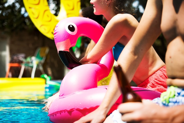 Um grupo diversificado de amigos, aproveitando o horário de verão à beira da piscina com carros alegóricos infláveis