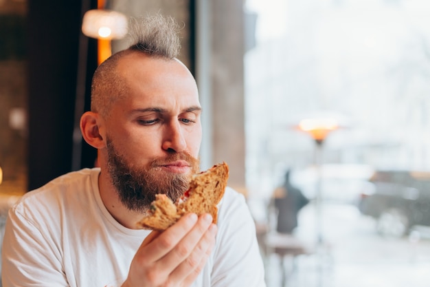 Um homem brutal de aparência europeia em um café com um sanduíche delicioso