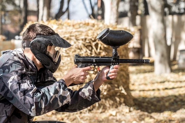 Um homem com uma arma jogando paintball.