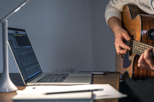 Um homem com uma guitarra na frente de um laptop, tarde da noite, aprende a tocar