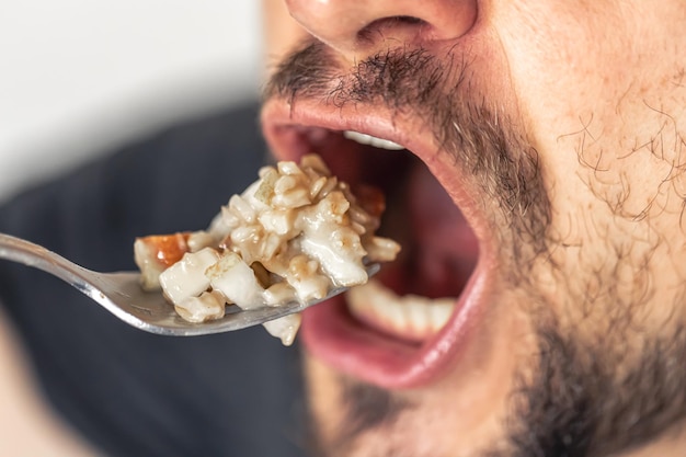 Foto grátis um homem come mingau com fruta a boca do homem está aberta