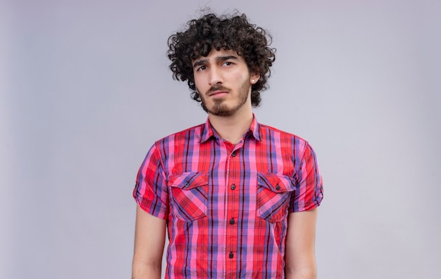 Um homem confuso e bonito com cabelo encaracolado e camisa xadrez pensando