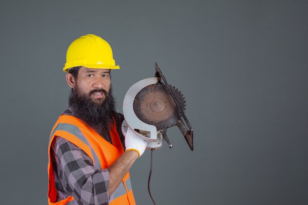 Um homem de engenharia usando um capacete amarelo com equipamentos de construção em um cinza.