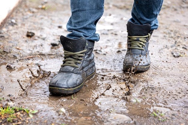 Um homem de jeans e botas caminha pelo pântano em tempo chuvoso