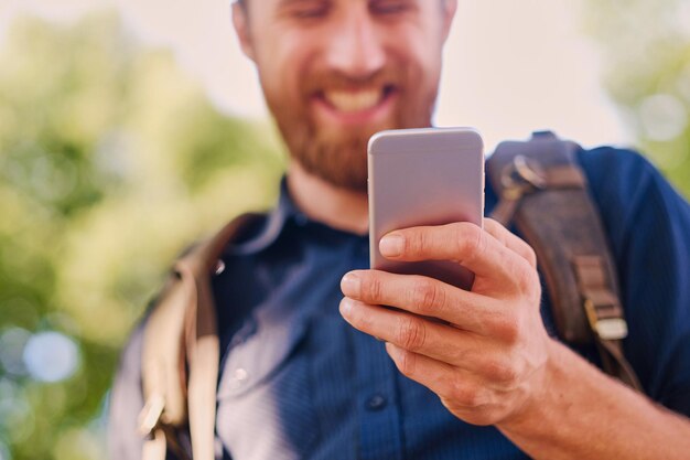 Um homem detém um telefone inteligente prateado. Fechar-se.