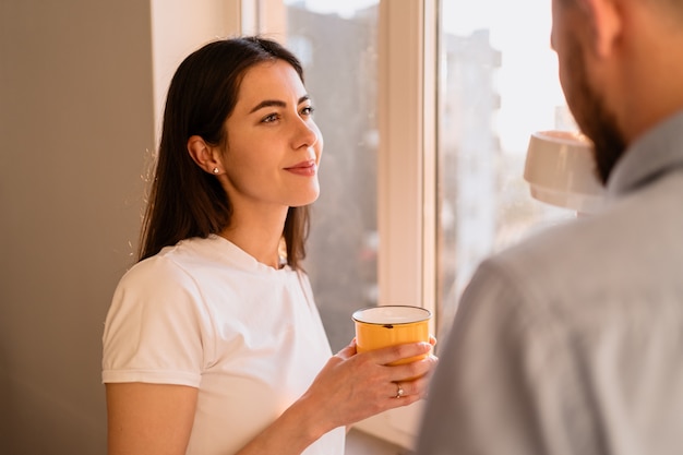 Um homem e uma mulher bebem chá perto da janela