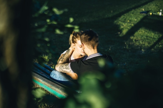 Um homem e uma mulher estão sentados em um banco e se beijando
