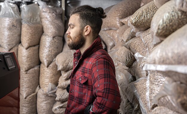 Um homem em uma sala com uma caldeira de combustível sólido, trabalhando com biocombustível, aquecimento econômico.