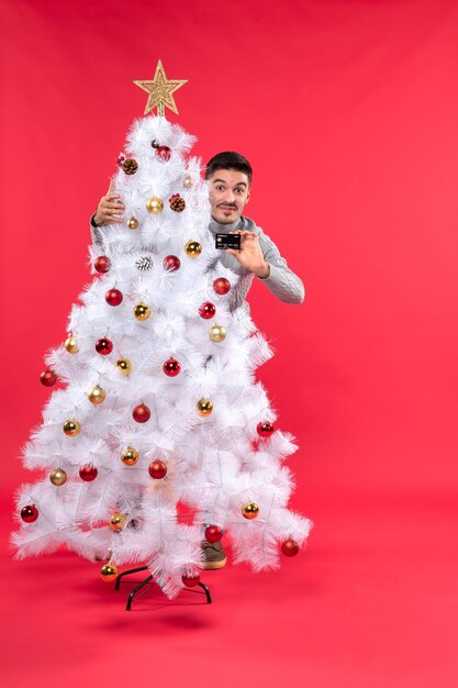 Um homem está parado ao lado da árvore de Natal