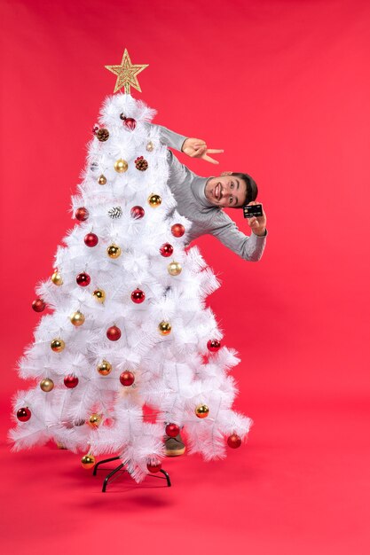 Um homem está parado ao lado da árvore de Natal