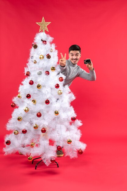 Um homem está parado ao lado da árvore de Natal