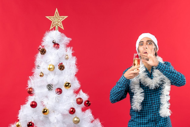 Um homem está parado ao lado da árvore de natal