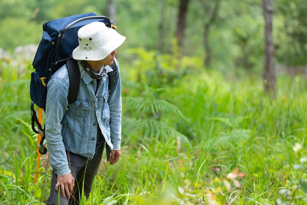 Um homem feliz caminhadas atravessa a floresta com uma mochila.