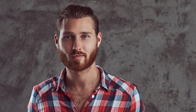 Um homem jovem modelo ruiva bonito em uma camisa de flanela em um fundo cinza.