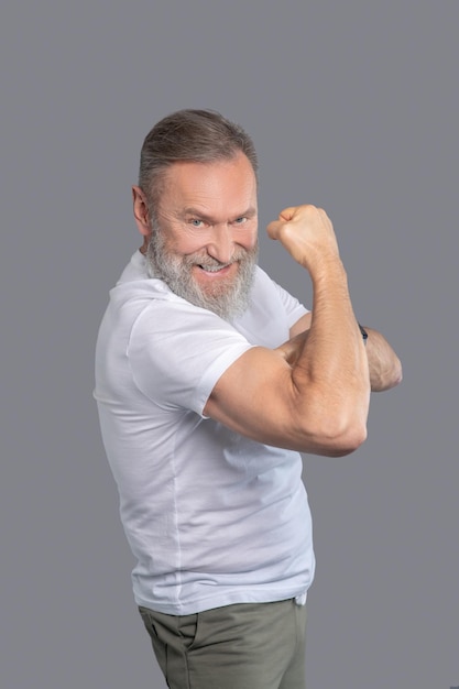 Foto grátis um homem maduro em uma camiseta branca mostrando seus músculos