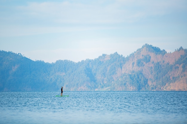 Um homem no lago monta uma prancha de supino.