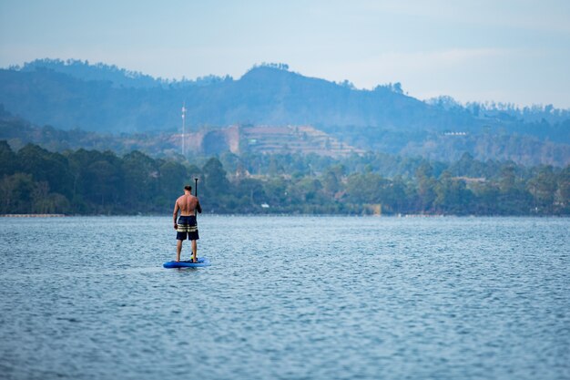 Um homem no lago monta uma prancha de supino.