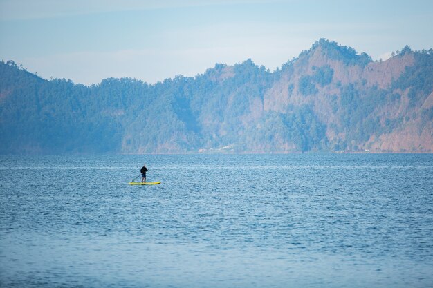 Um homem no lago monta uma prancha de supino.