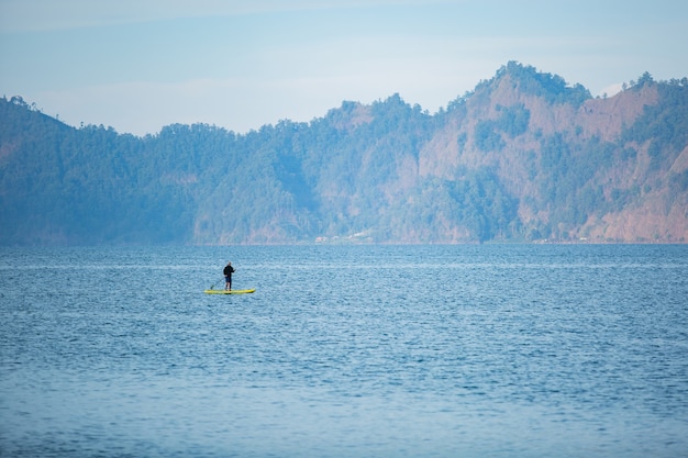 Um homem no lago monta uma prancha de supino.