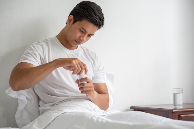 Um homem que não está bem no sofá e está prestes a tomar antibióticos.