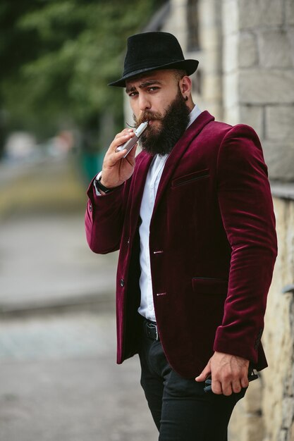 Um homem rico com barba fuma cigarro eletrônico