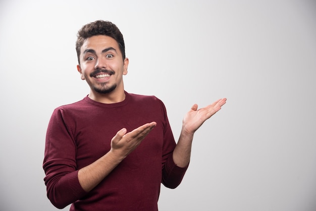 Um homem sorridente morena mostrando sua mão em um cinza.