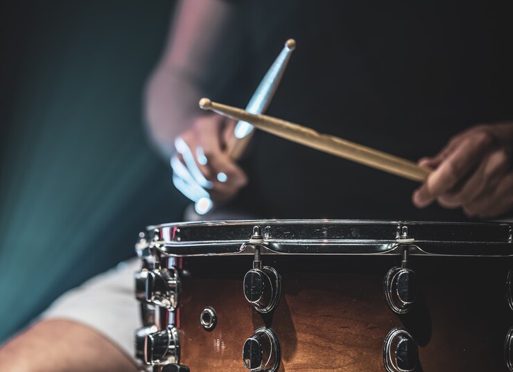 Foto grátis um homem toca baquetas em um tambor, um baterista toca um instrumento de percussão, copie o espaço.