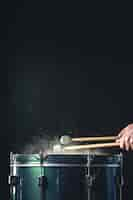 Foto grátis um homem toca um instrumento musical de percussão com paus em um fundo escuro