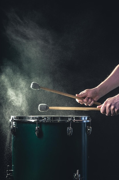 Foto grátis um homem toca um instrumento musical de percussão com paus em um fundo escuro