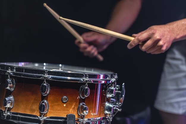 Um homem toca uma caixa com baquetas, um baterista toca um instrumento de percussão, close up.