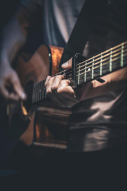Um homem toca uma guitarra acústica closeup