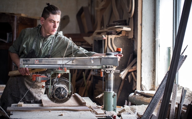 um homem trabalha na máquina com o produto de madeira