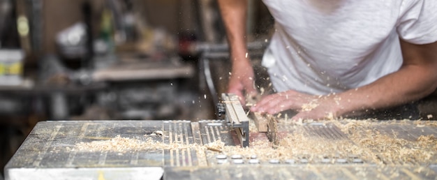um homem trabalhando com um produto de madeira na máquina, closeup