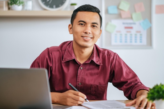 Um homem trabalhando em um escritório com papéis e laptop na mesa