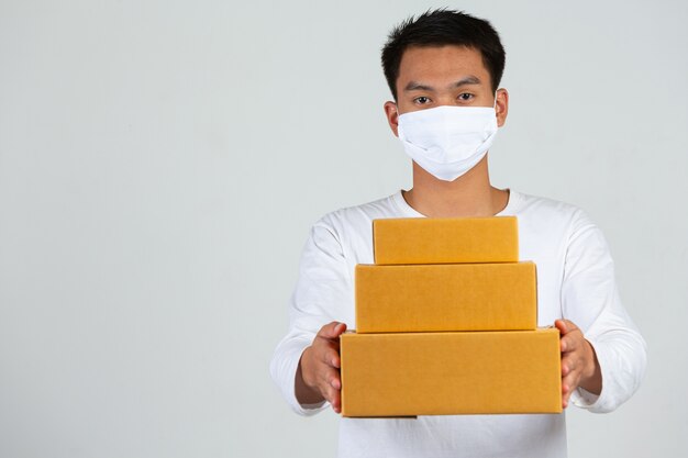 Um homem vestindo uma camiseta branca está segurando uma caixa de correio marrom para entregar coisas Faça gestos e expressões faciais.