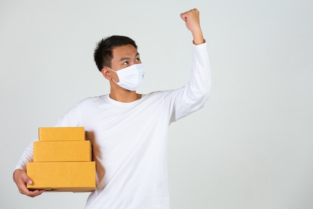 Um homem vestindo uma camiseta branca está segurando uma caixa de correio marrom para entregar coisas Faça gestos e expressões faciais.