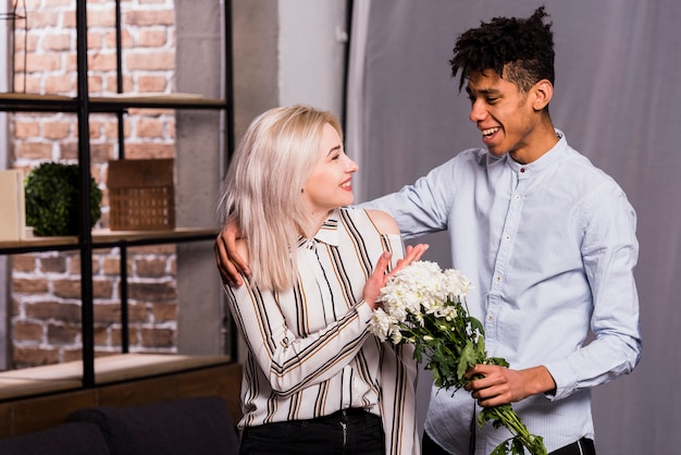 Foto grátis um jovem africano, propondo a namorada dando buquê de flores brancas