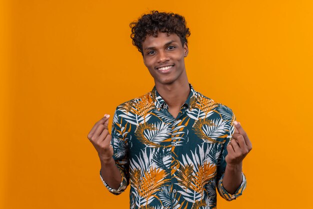 Um jovem bonito de pele escura com cabelo encaracolado em camisa estampada de folhas mostrando um gesto perfeito