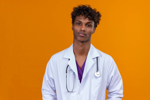 Um jovem bonito de pele escura com cabelo encaracolado, jaleco branco com estetoscópio e rosto triste