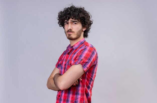 Um jovem bonito e rígido com cabelo encaracolado e camisa xadrez de mãos postas