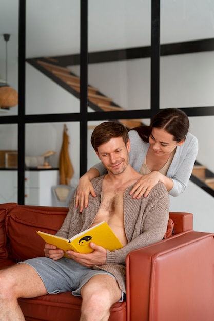 Foto grátis um jovem casal a ler na sala de estar.