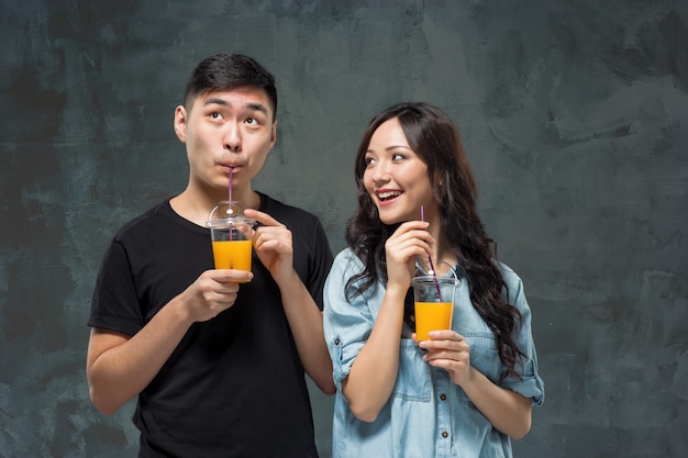 Um jovem casal asiático bonito com um copo de suco de laranja