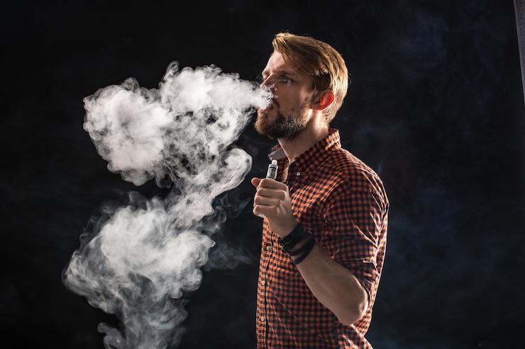 Foto grátis um jovem com barba e um penteado elegante em uma camisa, fumando um cigarro, uma víbora, um quarto, um estúdio, fumaça, prazer. fundo preto