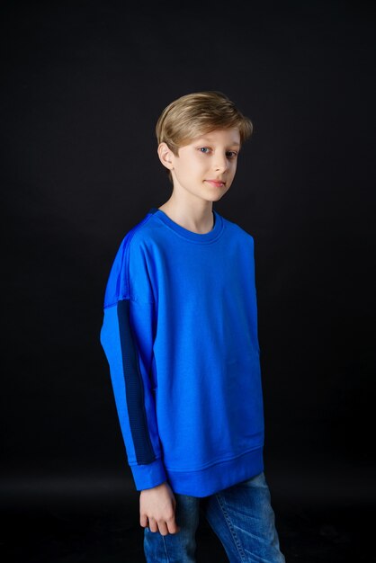 Um jovem com uma camiseta azul posando em um fundo preto