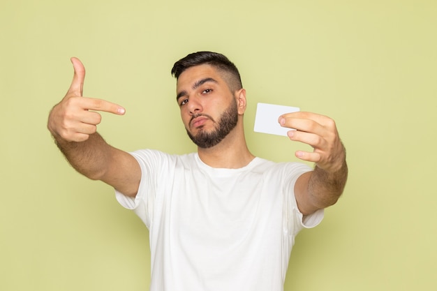 Foto grátis um jovem do sexo masculino com camiseta branca segurando um cartão branco