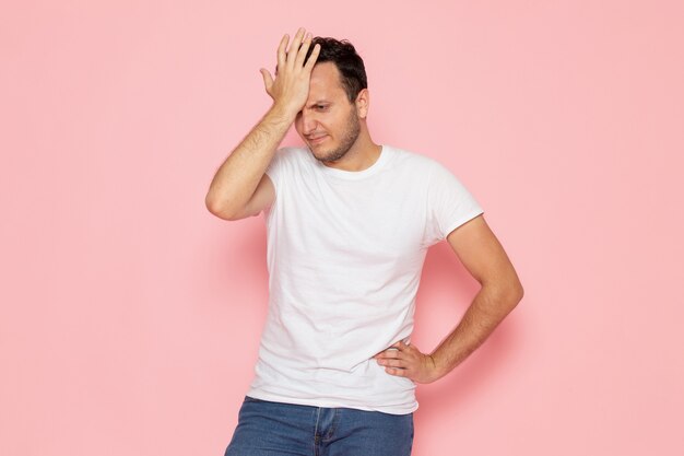 Um jovem do sexo masculino com uma camiseta branca posando com uma expressão desapontada