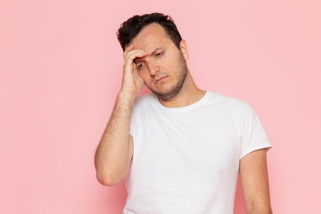 Um jovem do sexo masculino com uma camiseta branca posando com uma expressão estressada